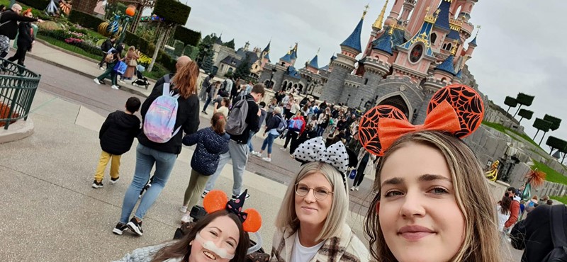 Claire and her PAs take a selfie in front of the Disney Castle with other people in the background