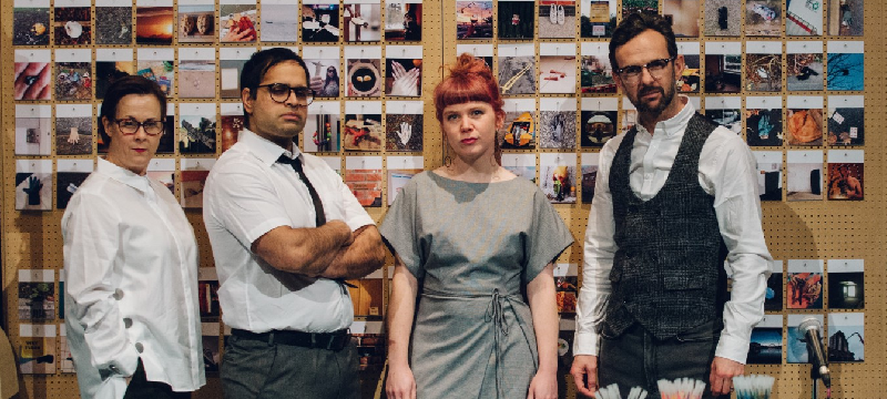 Photo of actors in office attire posing for the camera.