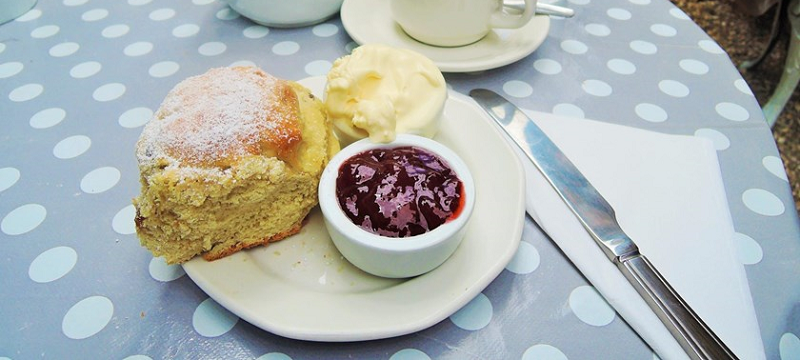 Photo of a scone with clotted cream and jam.