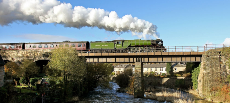 Photo of a steam locomotive crossing a bridge on the East Lancashire Railway.