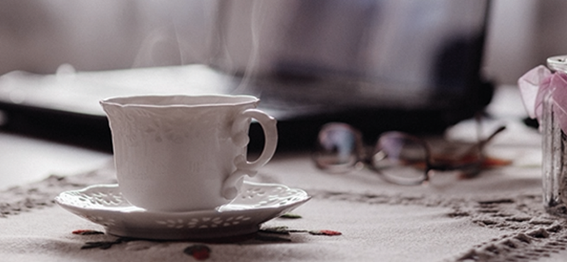 Image of a cup of hot tea sitting in front of a laptop