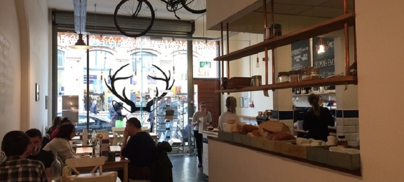 Interior of cafe. People are sitting at tables on the left hand side and the counter is to the right.