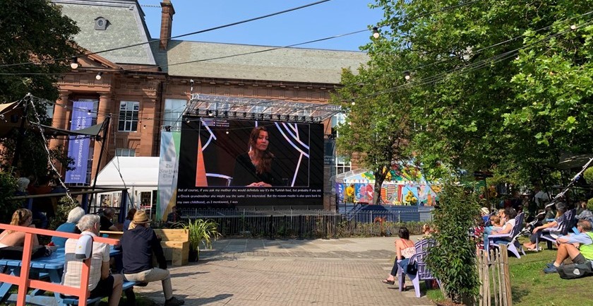 Courtyard at Edinburgh College of Art, the venue for the Edinburgh International Book Festival. Features folk watching a big screen of a performance happening indoors.