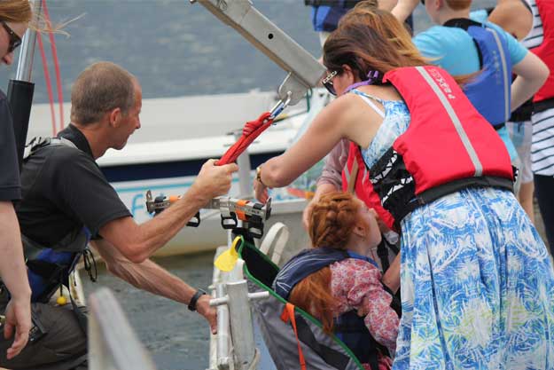 A photo of a young woman being lowered into a sailing boat.