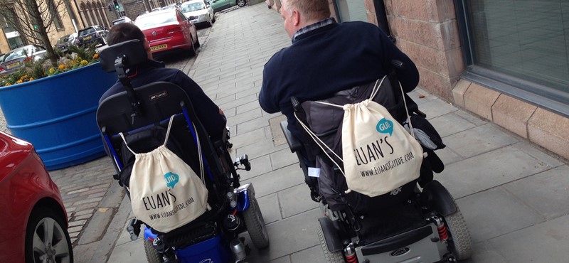 A photo of two people walking down a street.