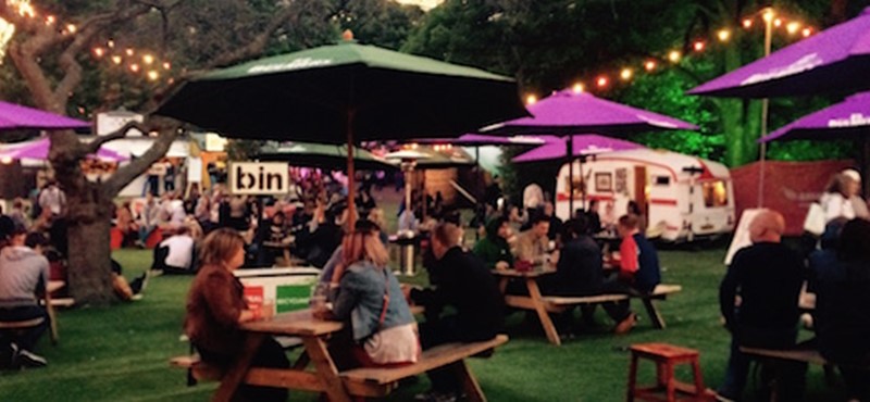 People sitting in George Square gardens with fairy lights during the Fringe.