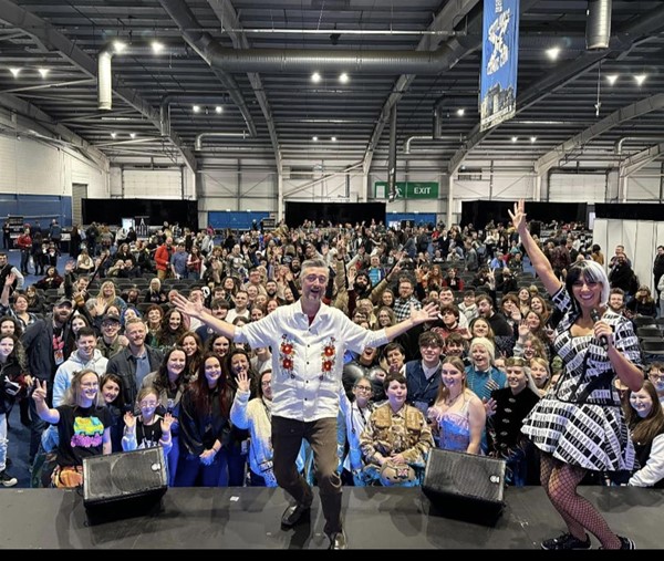 Image of a man on stage facing away from a crowd