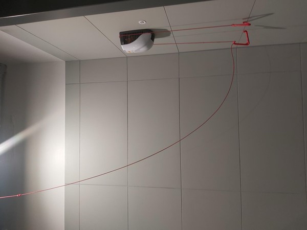 Image of a white tile wall with a red emergency cord attached to it