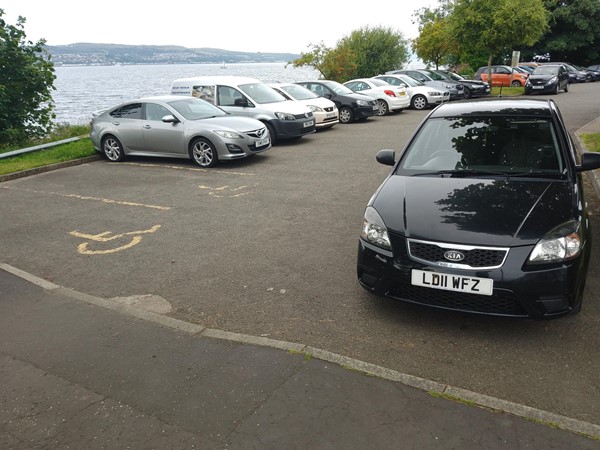 Image of a car park with cars parked by the water