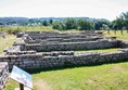 Roman ruins of several rooms with grass inside and out.