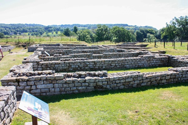 Roman ruins of several rooms with grass inside and out.