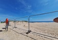 Image of a fenced area with a beach and blue sky