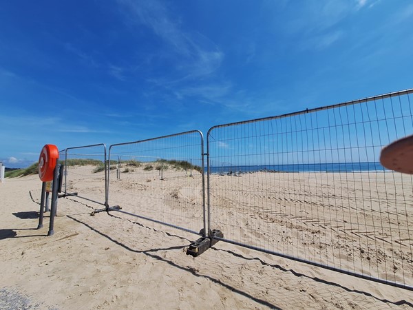 Image of a fenced area with a beach and blue sky