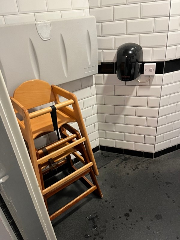 Image of a high chair being stored in the accessible toilet