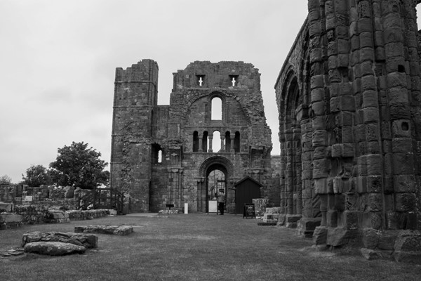 Monochrome photo of priory entrance with grass area in front.