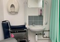 Image of the sink, private screen, bin and manual wheelchair in the accessible toilet.