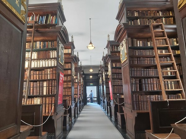 Image of a long hallway with bookshelves and ladders