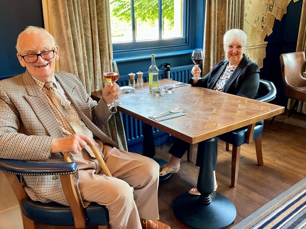 Image of  aperson and person sitting at a table with wine glasses