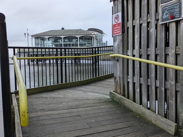 Image of ramp access to the pier. Wooden boards with rails on both sides