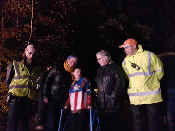 Child (walker user) and two women standing with two security staff