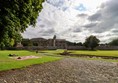 Museum grounds with cobbles and a rough path up to the gate.