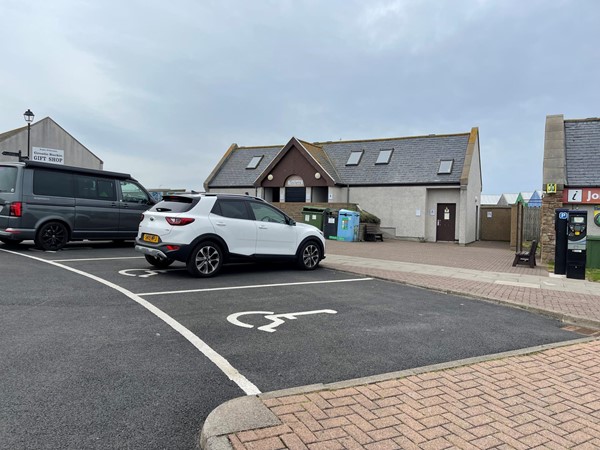 The accessible parking bays in the car park. The toilet building with the accessible toilet is in the background.