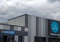 Image of a a grey and blue building with a sign that says "Greggs"