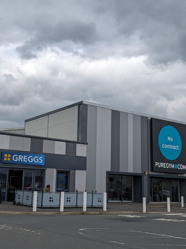 Image of a a grey and blue building with a sign that says "Greggs"