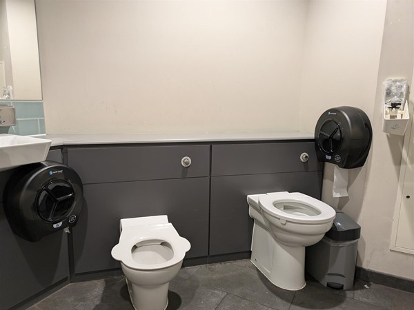 Image of the family toilet at Cairn Lodge Services, a high and low toilet seat side by side.