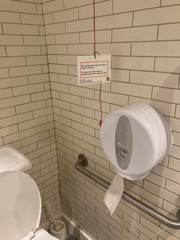 Image of an accessible toilet with a cut short red cord