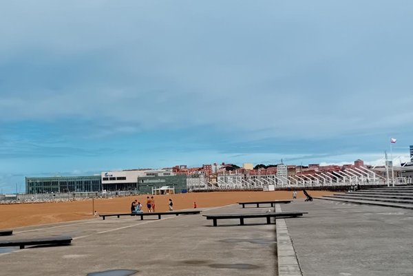 If you're standing here on the promenade at Poniente beach, you're facing the right way to reach the beach wheelchair station. Keep going around the promenade until you reach the end,  The hut is in front of the large concrete building with the word on it that you can see in the distance.