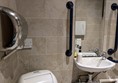 Image of the accessible toilet showing a hand dryer and the sink and mirror, with grab rails on either side.