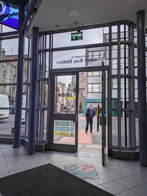 A glass door to a bus station