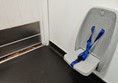 Fold-down seat cannot be fixed in the up position, an obstruction for wheelchair users entering the toilet vestibule area