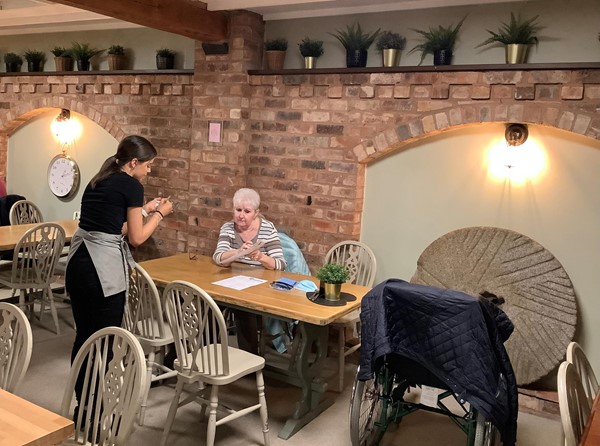 Picture of a member of staff taking an order at a table