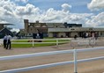 Image of a horse race track with a building and a fence