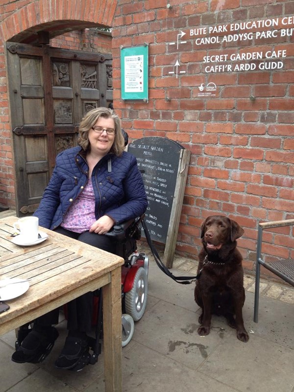 Picture of a lady in a powerchair, with a brown laborador, at Bute Park