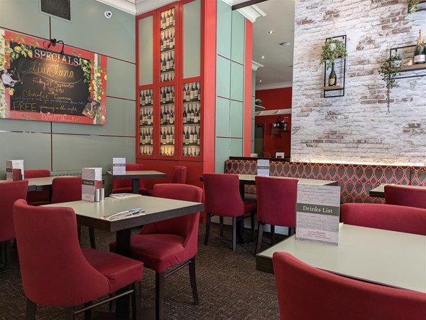 Image of the seating area within the restaurant. Small tables with comfortable red chairs