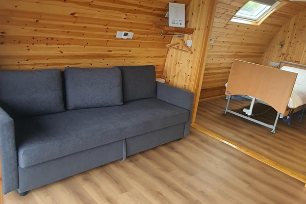 Image of the living room area of the accessible glamping pod including the pull out sofa bed.