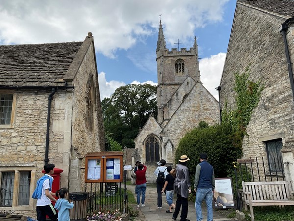 Image of a group of people walking in a courtyard with  a church in the background