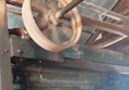 There is a yellow metal wheel that is part of the machine spinning in the shed. end Description.