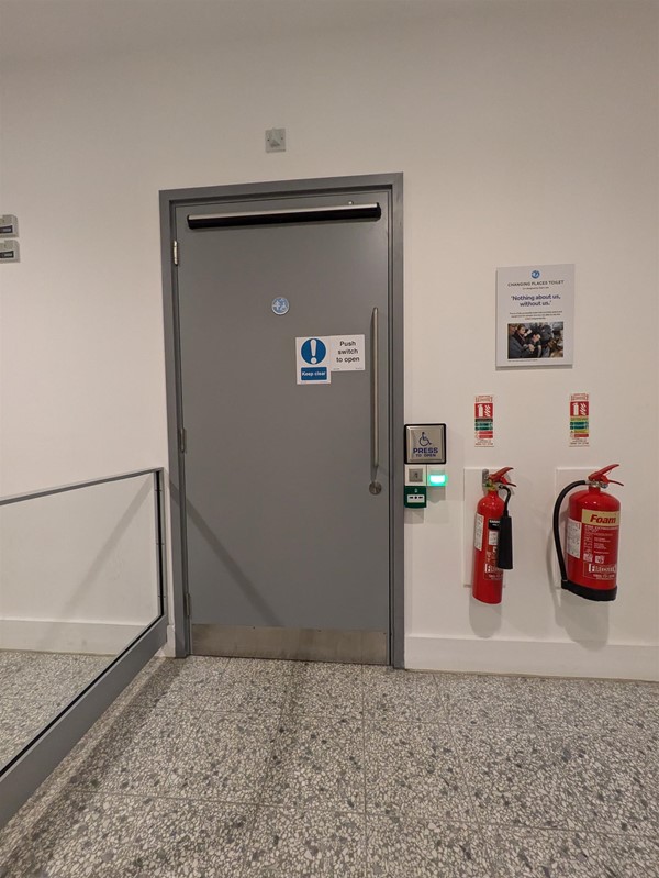 Entrance to the toilet, a push button on an off-white wall