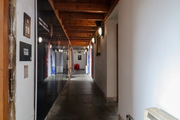 Upper corridor with exhibtion on the left and doors on the right.