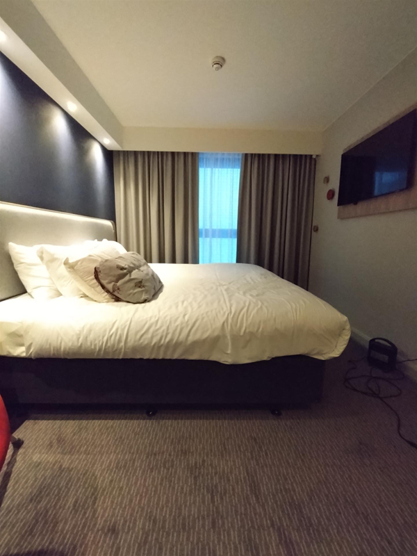 The accessible room. Queen bed, telly on the wall, a high back egg-shaped sort of armchair just out of view on the left. That's my own two pillows you can see in the photo up against the 2 standard hotel pillows, with a second set further along nearer the window just out of view.