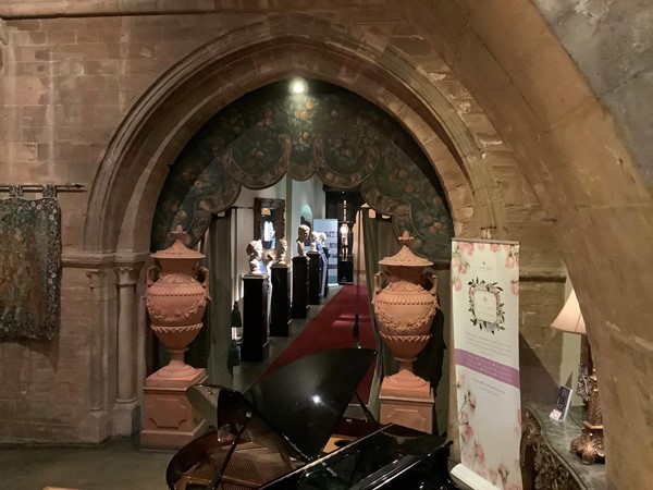 Picture of an archway leading to a corridor with roman busts lining it