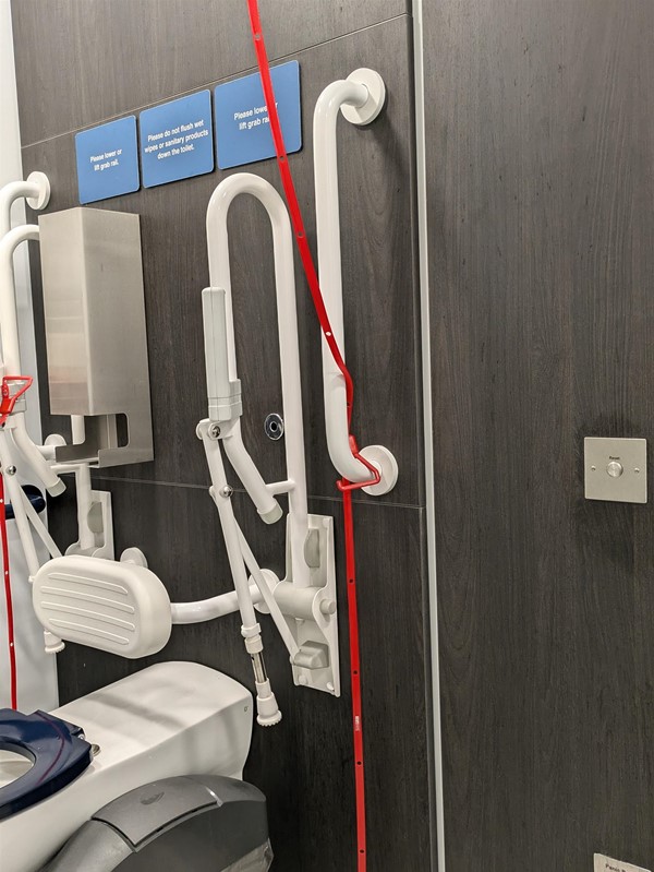 Image inside the disabled toilet showing the red strap tied around the grab rail.