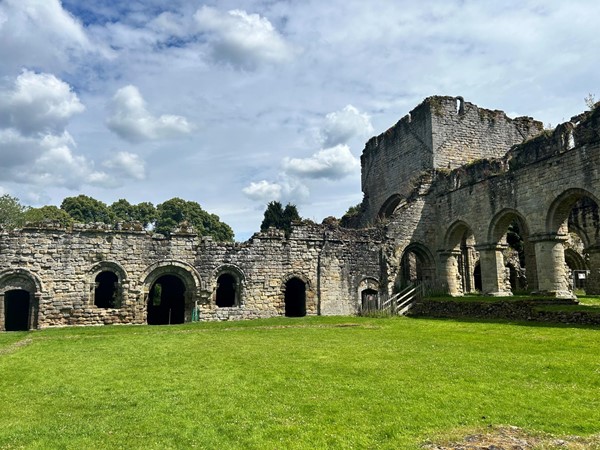 Image of a stone building with arches and grass