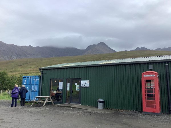 Image of a green corrugated metal building with a phone box outside