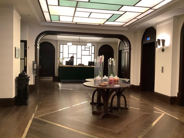 The hotel lobby featuring a circular table in the centre with dark flooring and ceiling panel lights