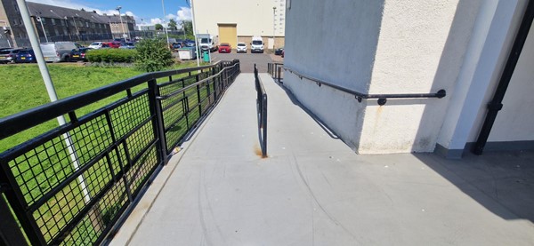 Image of a ramp with a railing leading up from the carpark